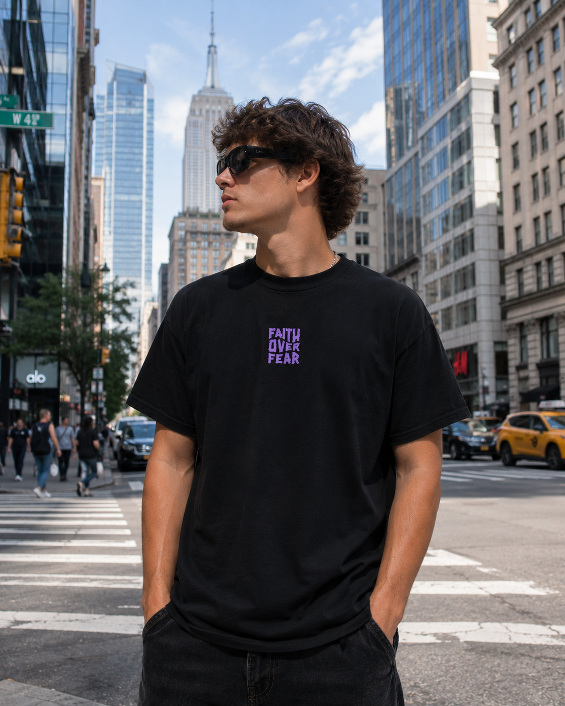 Man wearing a black Holy Wear Faith Over Fear t-shirt on a city street